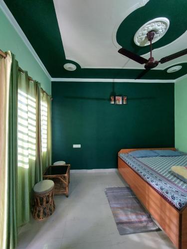 1 dormitorio con paredes verdes y 1 cama con techo en Anjali Home Stay, en Rishīkesh