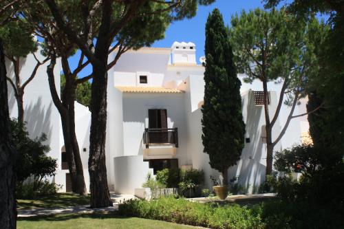 a white house with trees in front of it at Pine Cliffs Village in Albufeira