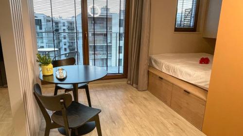 een kleine kamer met een tafel, een bed en een raam bij Comfortable 1-room apartment close to the center in Warschau