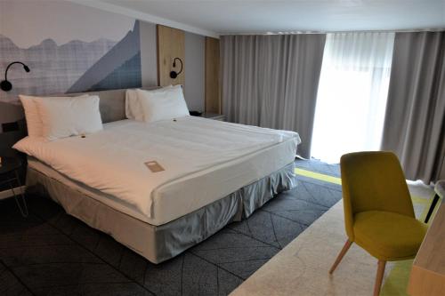 a hotel room with a bed and a chair at Mandachi Hotel & SPA in Suceava