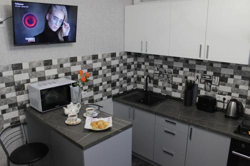 a kitchen with a microwave and a tv on the wall at Квартира в Вышгороде для души in Vyshhorod