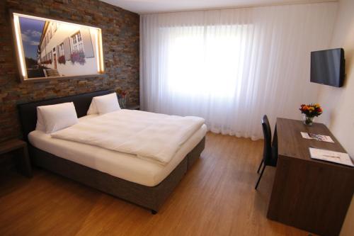 a bedroom with a bed and a desk and a window at Hotel Eremitage in Arlesheim