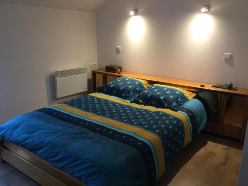 a bedroom with a bed with blue sheets and pillows at Hébergement à l'Orée des Champs in Rethel