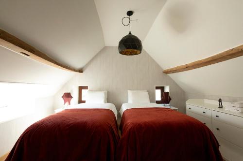 a attic bedroom with two beds with red blankets at Enjoytoday 49 - Luxueus familieverblijf aan de voet van de Koppenberg in Oudenaarde