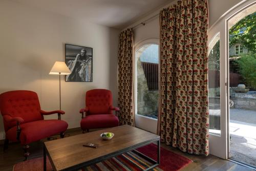 a living room with two red chairs and a table at Le Prieure in Villeneuve-lès-Avignon