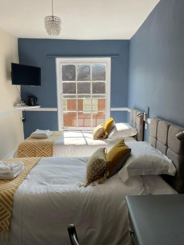 a blue bedroom with two beds and a window at The White Hart in Whitchurch