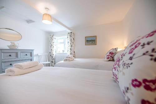 a bedroom with two beds and a mirror at North Cottage, Alderton in Woodbridge