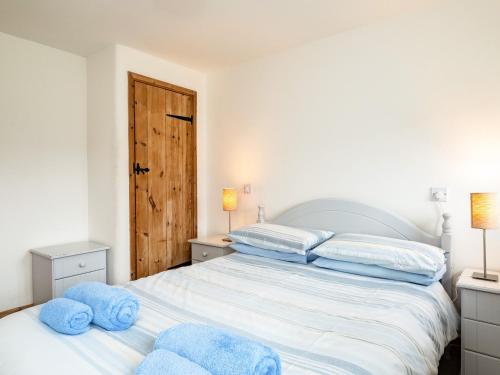 una camera da letto con un grande letto bianco con cuscini blu di Swallow Cottage, Trewetha Farm a Port Isaac