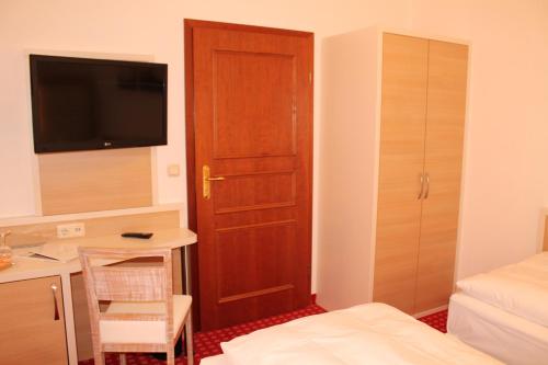 a small room with a bedroom with a desk and a door at Hotel Fürsteneck in Bernburg