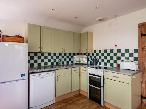 a kitchen with white appliances and green and white tiles at Gull Lodge in Port Isaac