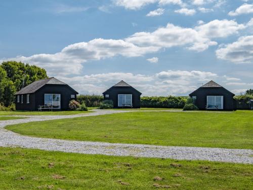 two houses on a grassy field with a gravel road at Gull Lodge in Port Isaac