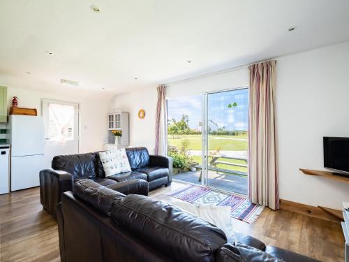 a living room with a leather couch and a sliding glass door at Harbour Lodge in Port Isaac