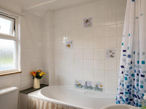a white bathroom with a tub and a vase of flowers at Harbour Lodge in Port Isaac