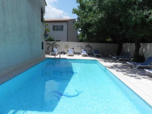 uma grande piscina azul com cadeiras e um edifício em Motel Cap Sol em Mandelieu-la-Napoule