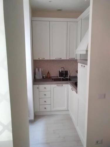 a white kitchen with white cabinets and a sink at La Casa di Ludovica all'Appio Latino in Rome