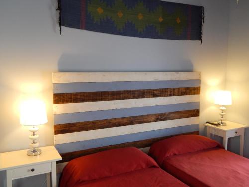 a bedroom with two red beds and two lamps at Hospederia Marqués in Cádiz