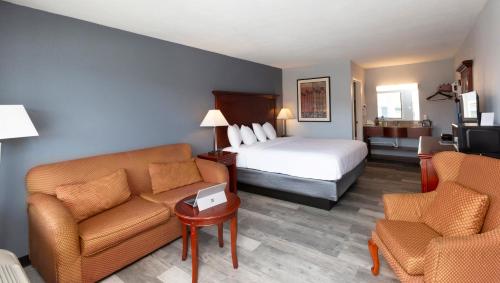 a hotel room with a bed and a couch and chairs at Sunrise Inn Williamstown in Williamstown