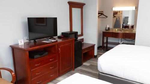 a hotel room with a bed and a television on a dresser at Sunrise Inn Williamstown in Williamstown