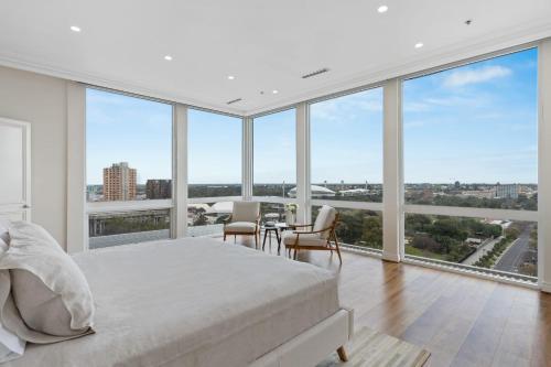 a bedroom with a white bed and large windows at Swainson at M1 - Penthouse in Adelaide