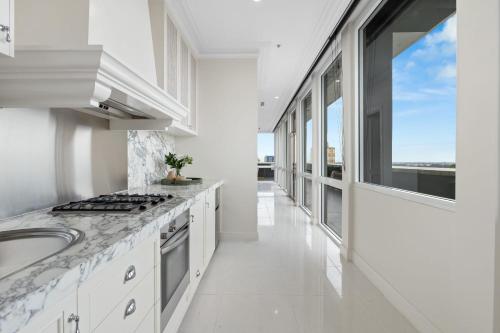 a white kitchen with a sink and a large window at Swainson at M1 in Adelaide