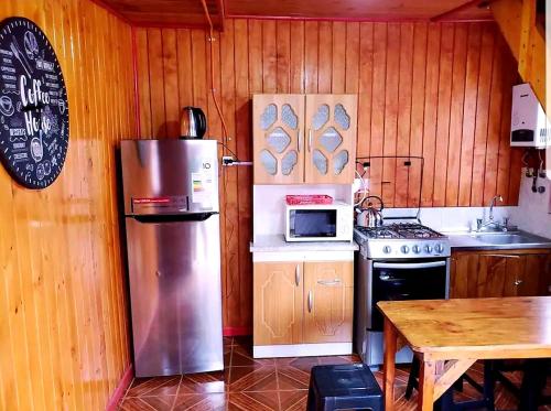 a kitchen with a stainless steel refrigerator and a table at Cabaña Isla Negra in Isla Negra