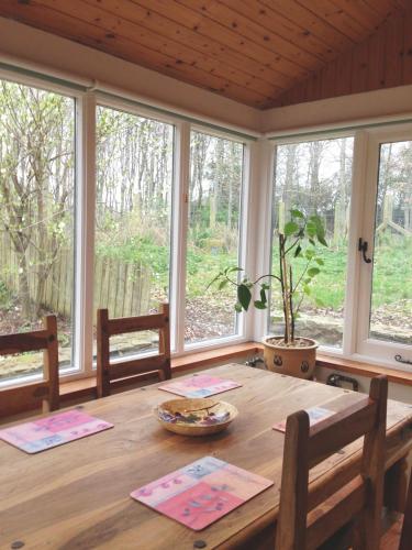 a wooden table in a room with windows at Berwick Hall Cottage in Moira