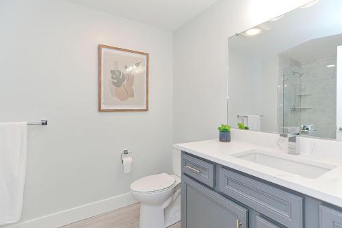 a bathroom with a sink and a toilet and a mirror at Harbourtown Suites on Plymouth Harbor in Plymouth