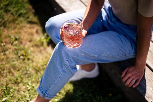 a person sitting on a bench holding a wine glass at Hotel Gasthaus Post in Campo di Trens