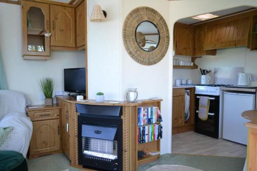 a kitchen with wooden cabinets and a book shelf at Swallows Return in Clynderwen