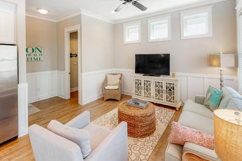 a living room with white furniture and a flat screen tv at Cool Breeze in Gulf Shores