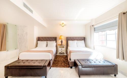 a room with two beds and a bench in it at Secret Garden Miami Beach in Miami Beach
