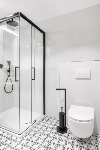a white bathroom with a shower and a toilet at Hotel Vestina in Wisła