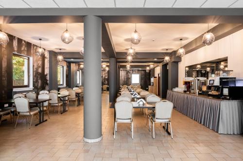 a dining room with tables and white chairs at Hotel Vestina in Wisła