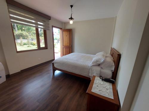 a bedroom with a bed and a table and a window at Quinta San Felipe in Tababela