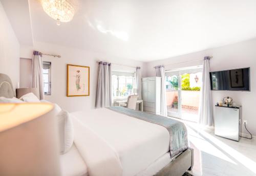 a white bedroom with a large bed and a window at Secret Garden Miami Beach in Miami Beach