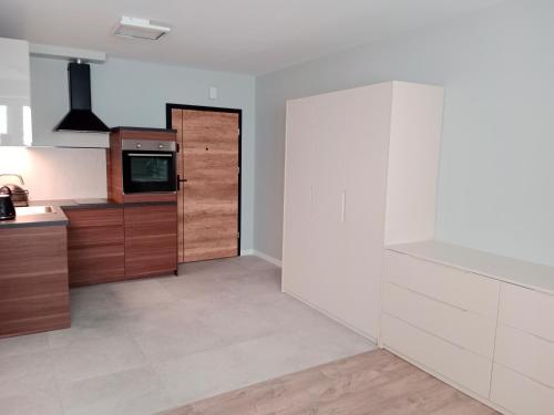 a kitchen with white walls and wooden cabinets at Apartamenty Radom Klwatecka 20 in Radom