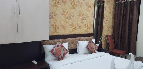 a bedroom with a bed with white sheets and red pillows at Hotel Teeja's - Haldi Restaurant Aiims road Jodhpur in Jodhpur