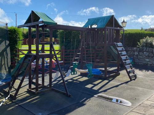 a wooden playground with a slide and a play structure at The Hilltop Haven in St Asaph