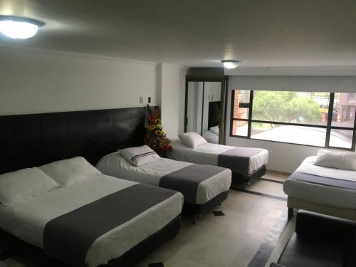 a hotel room with three beds and a window at Hotel Ejecutivo Av la Esperanza in Bogotá