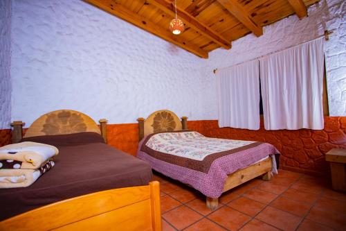 a bedroom with two beds and a wooden ceiling at Cabañas RuizSeñor in Mazamitla