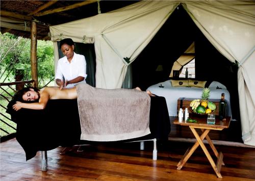 a woman laying in a chair in front of a tent at Karen Blixen Camp Masai Mara in Narok