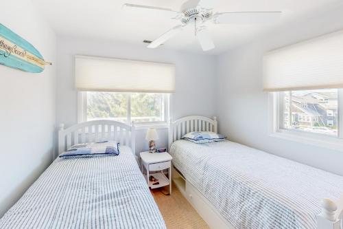 two beds in a bedroom with white walls and windows at Sandywalk -- South Atlantic 26 in Bethany Beach