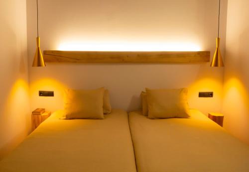 two beds in a room with lights on them at Domus Oncinae in Oncina de la Valdoncina