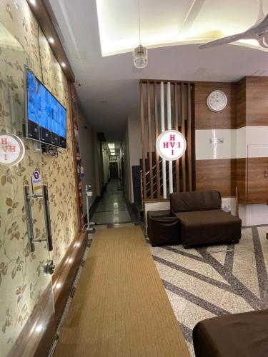 a lobby with a couch and a clock on the wall at Hotel vinayak inn in Haridwār