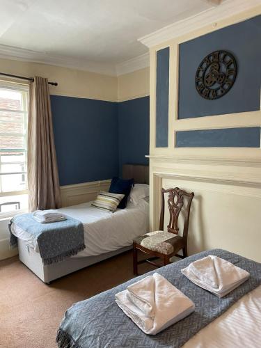 a bedroom with two beds and a chair and a window at The White Hart in Whitchurch