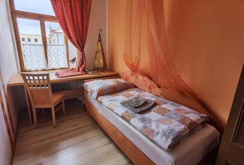 a bedroom with a bed and a desk and a window at U Černého orla in Vidnava