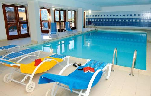 - une piscine avec 2 chaises et une table dans l'établissement Appartement 6 personnes - Deux chambres - 40M2 - Balcons 10M2 sur pistes - Aucun vis à vis - Piscine - B301, à Orcières