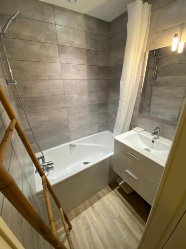 een badkamer met een wit bad en een wastafel bij Côté lac in Gérardmer