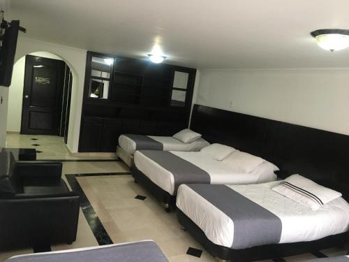 a hotel room with three beds and a black door at Hotel Ejecutivo Av la Esperanza in Bogotá