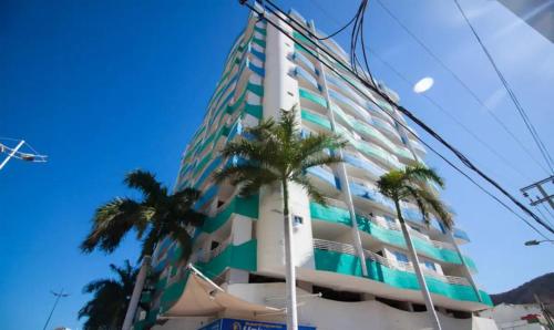 un edificio alto con palmeras delante en Apartamentos con vista al mar Brisa Marina Rodadero - by Bedviajes, en Santa Marta